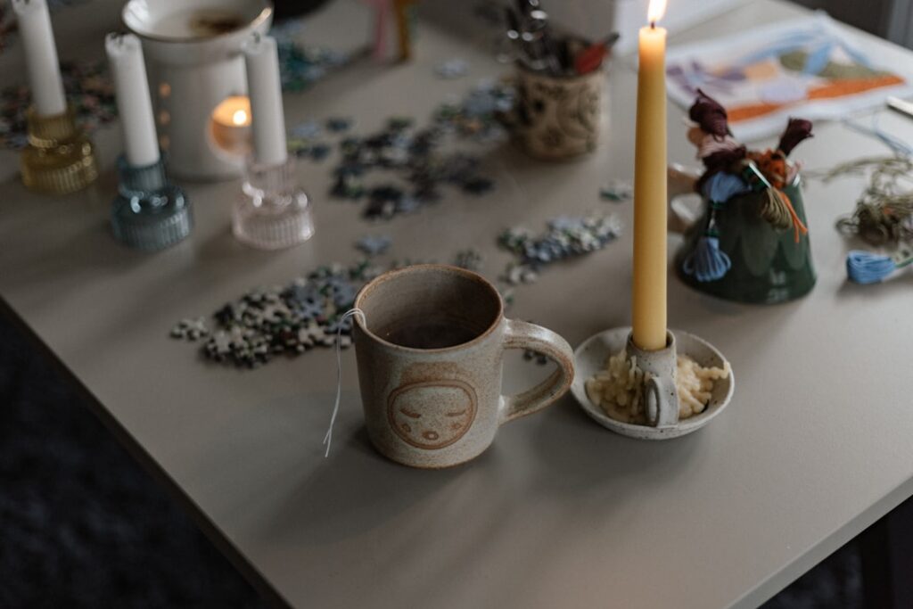 A table topped with a candle and a cup of coffee