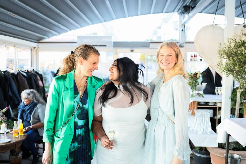 Three women smiling and talking at an outdoor event