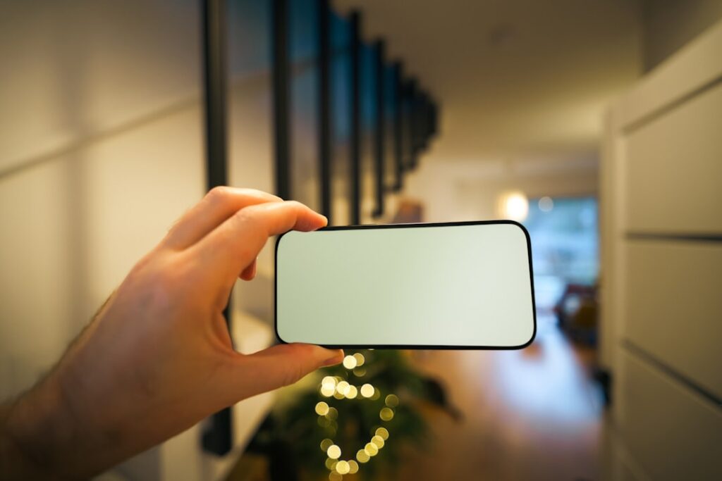 Hand holding smartphone with blank screen indoors