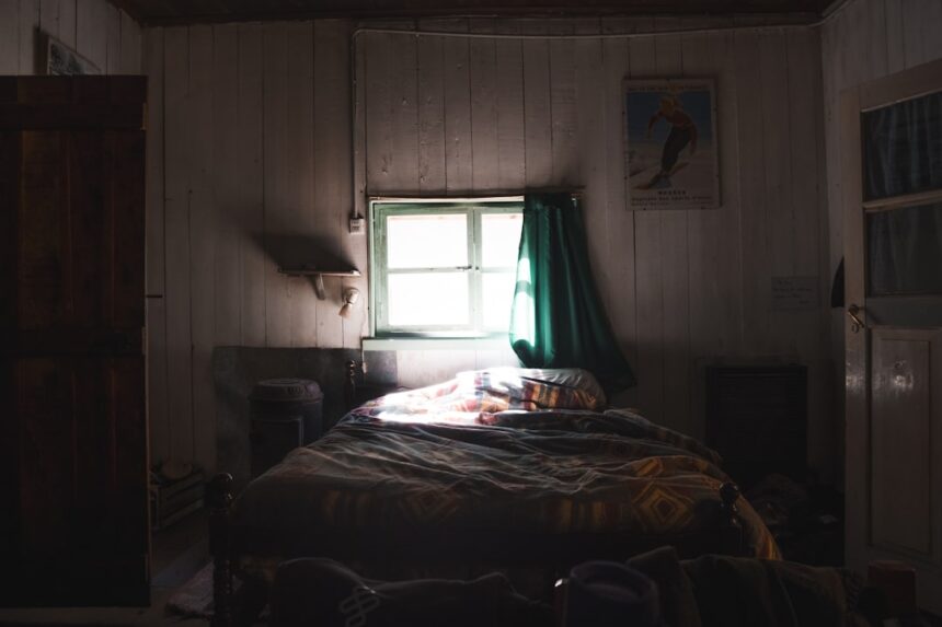 Dimly lit bedroom with a bed and window.
