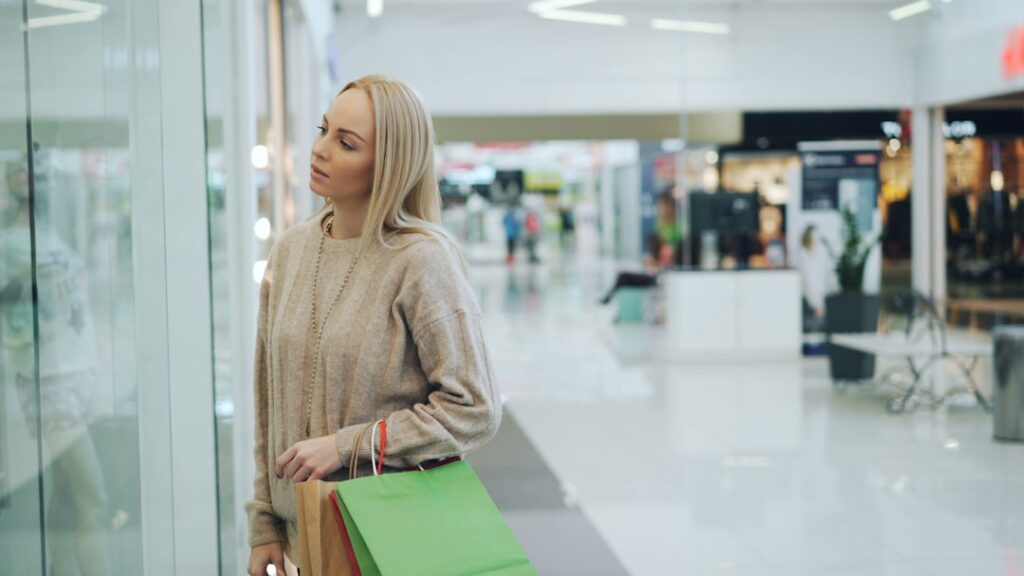 Woman looking into a shop window with shopping bags
