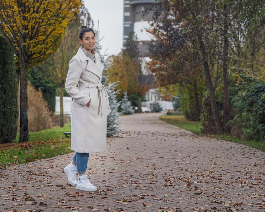 a woman in a trench coat standing on a sidewalk
