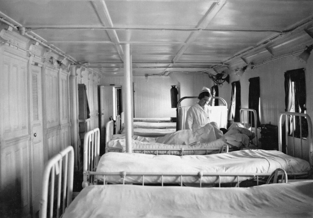 Hospital ward with beds and a nurse attending patient