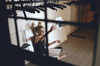 Young woman sitting on floor, throwing papers