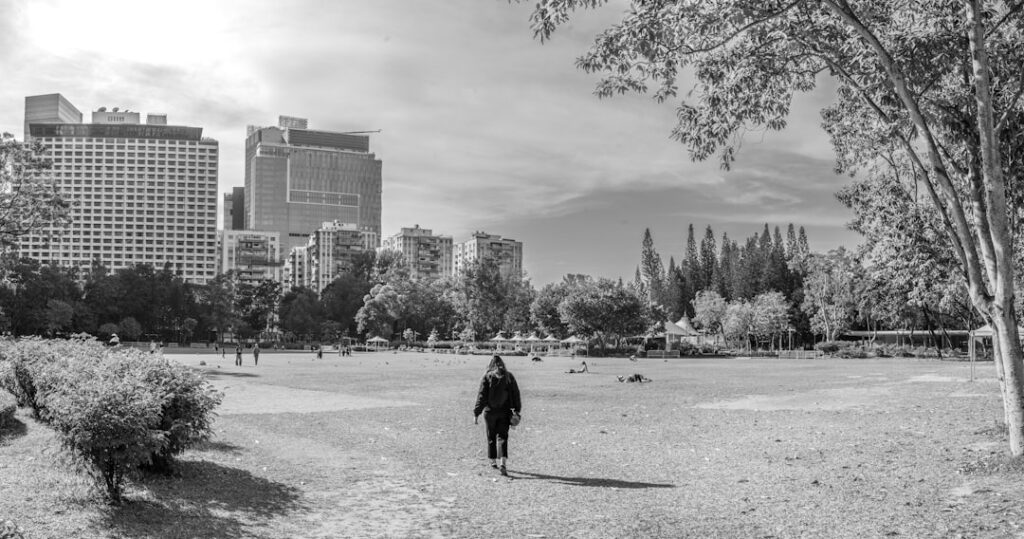Person walking in a park with city buildings behind
