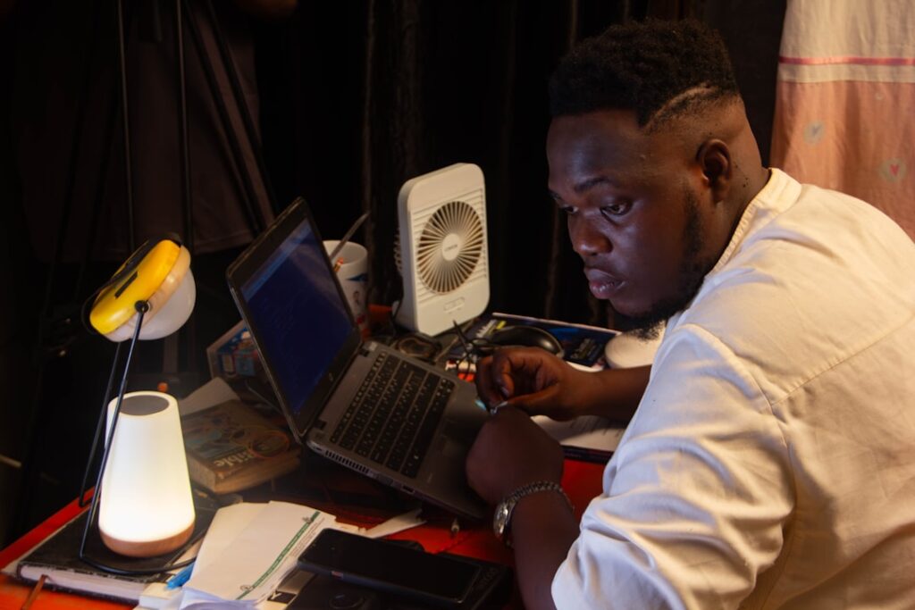 Man working on a laptop with desk lamps.