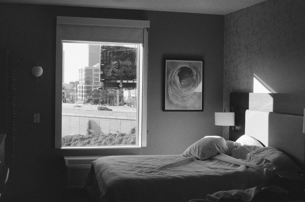 Bedroom with a large window overlooking a city street.