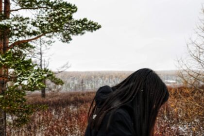 a woman with long hair standing in a field