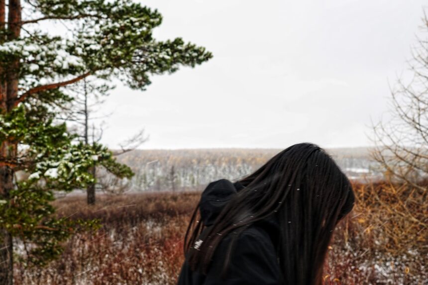 a woman with long hair standing in a field