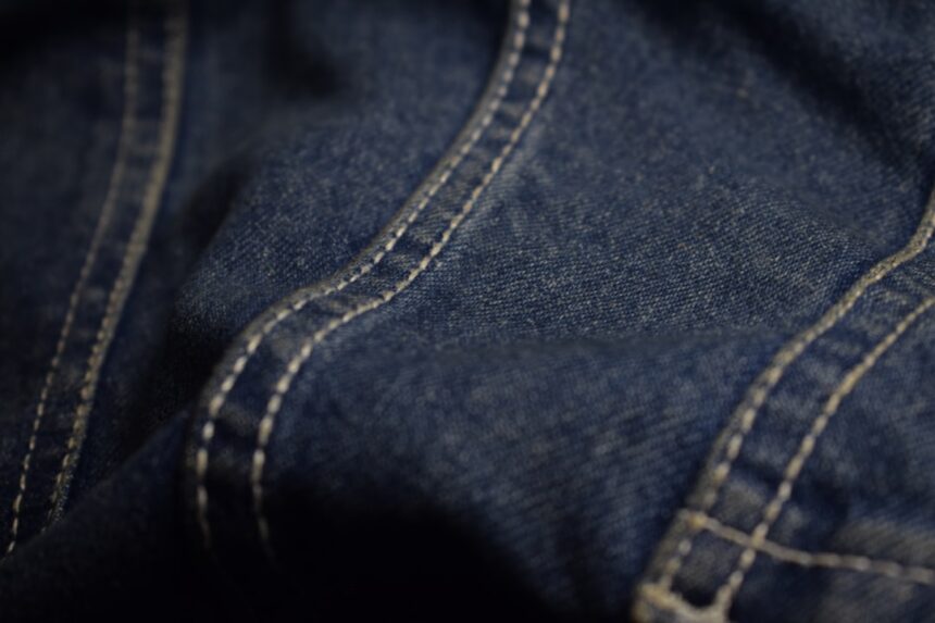 Close-up of blue denim fabric with white stitching
