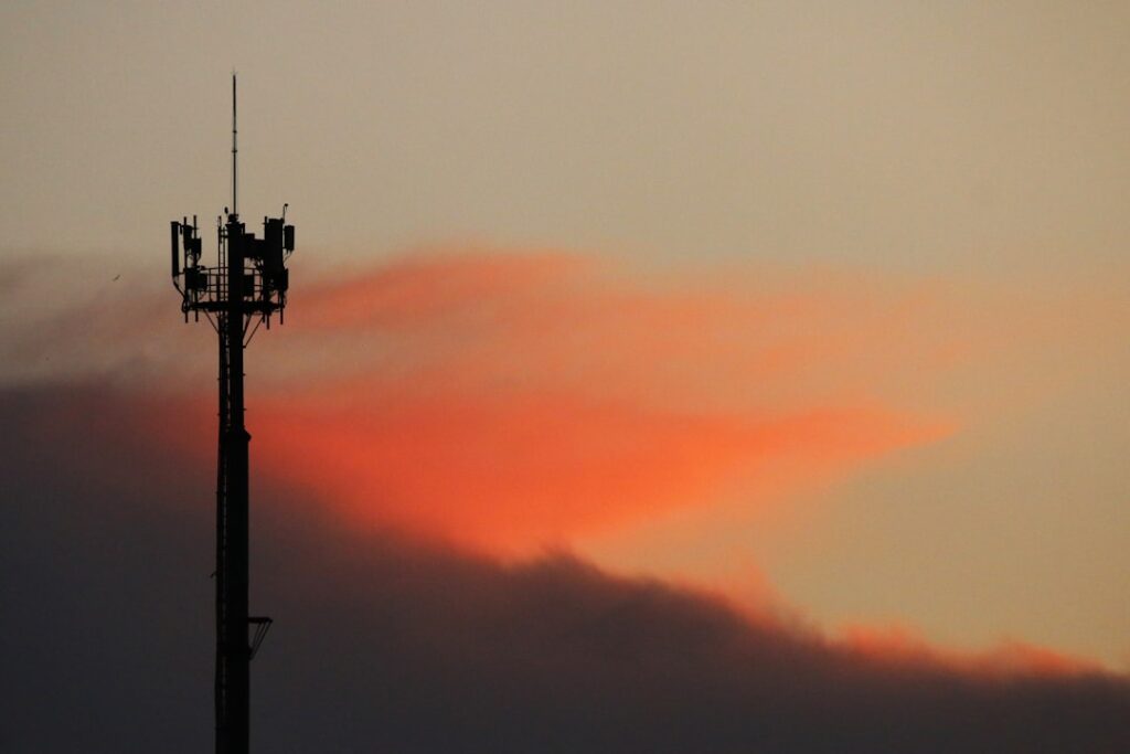 Cell tower silhouetted against a sunset sky