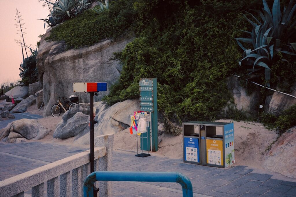 Street sign and trash bins near rocky hillside