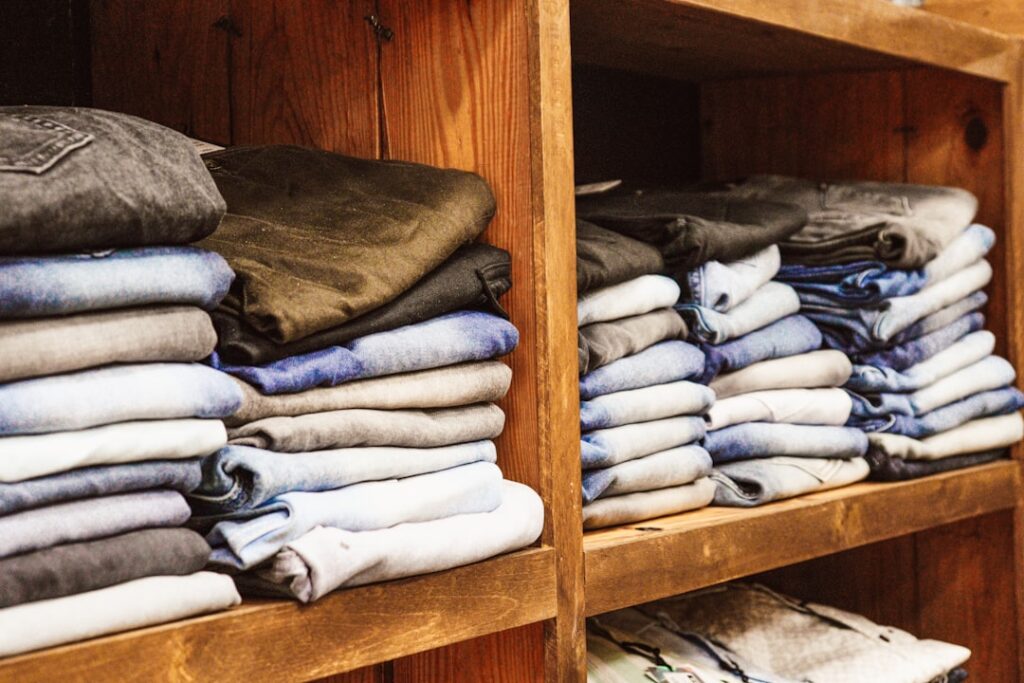 a wooden shelf filled with lots of folded clothes