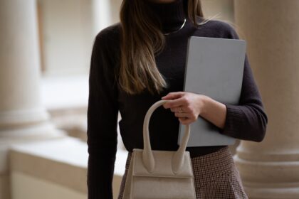 Woman holds a bag and a computer.