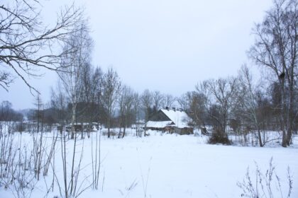 Snow-covered landscape with a rustic wooden house.