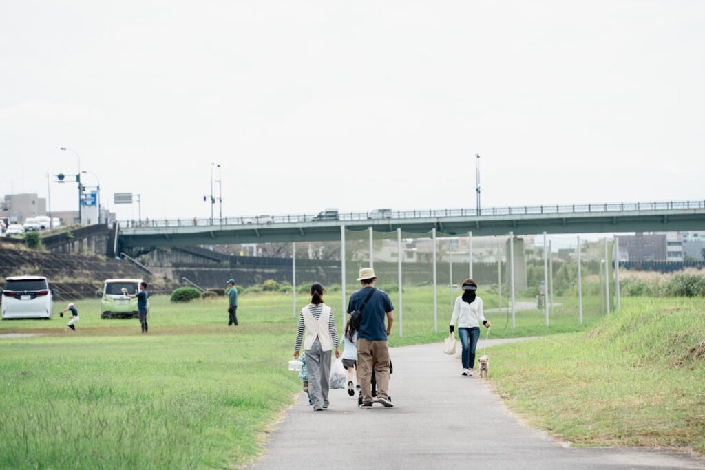 People walking on a path by a grassy riverbank