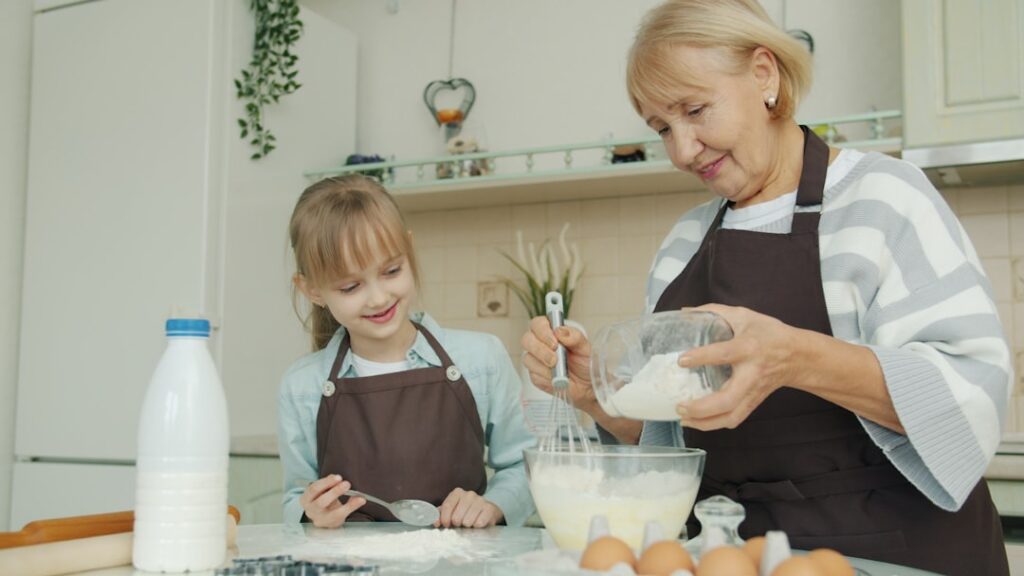 Grandmother and granddaughter baking together in a kitchen.