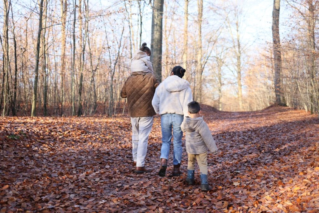 Family walking on a path covered in autumn leaves