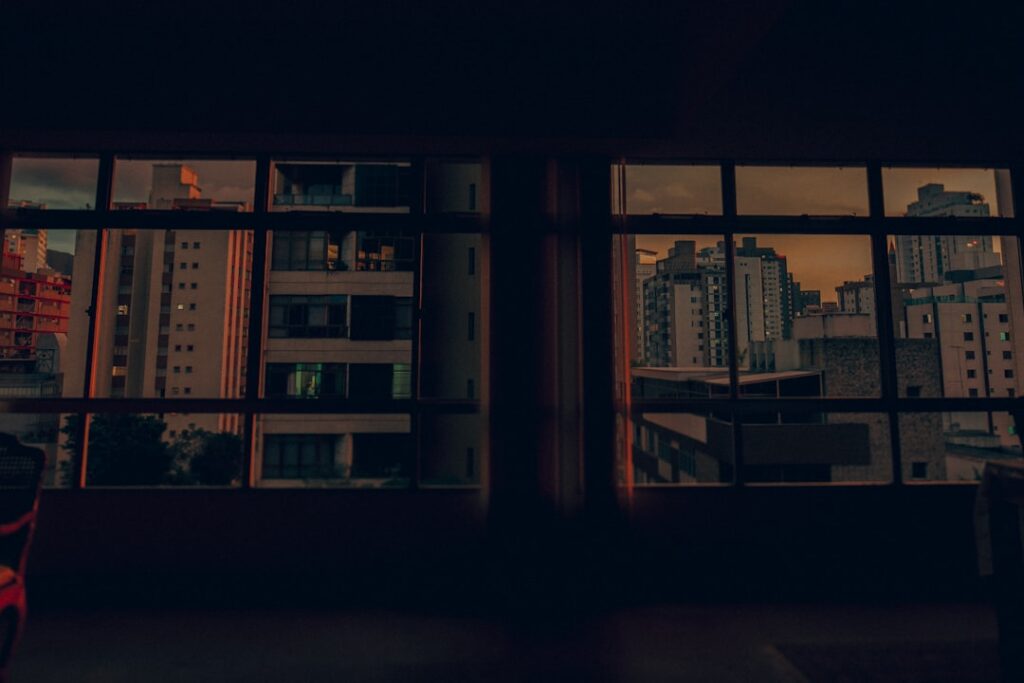Cityscape visible through apartment windows at dusk.