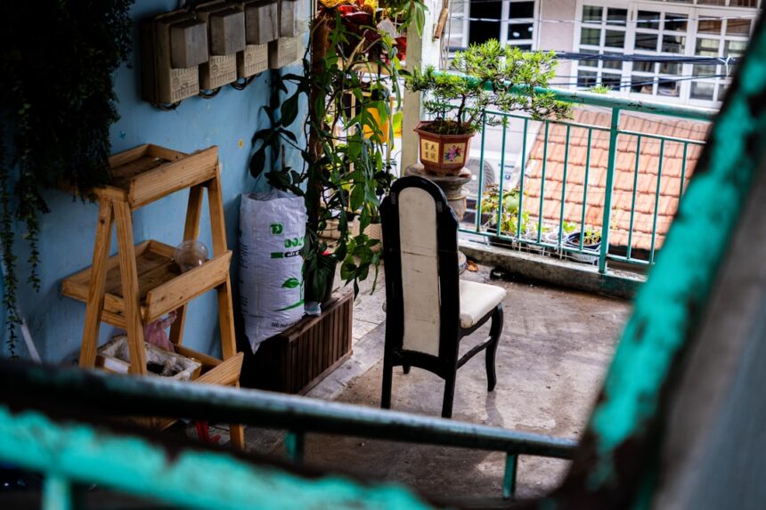 Balcony with chair, plants, and wooden shelf.