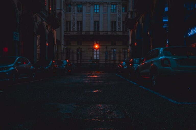 a city street at night with cars parked on the side of the road