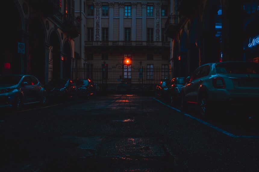 a city street at night with cars parked on the side of the road