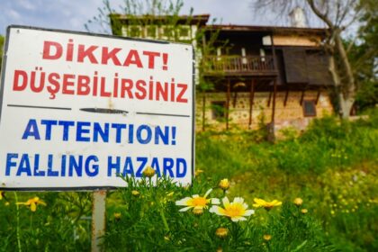 a sign that is in the grass near flowers