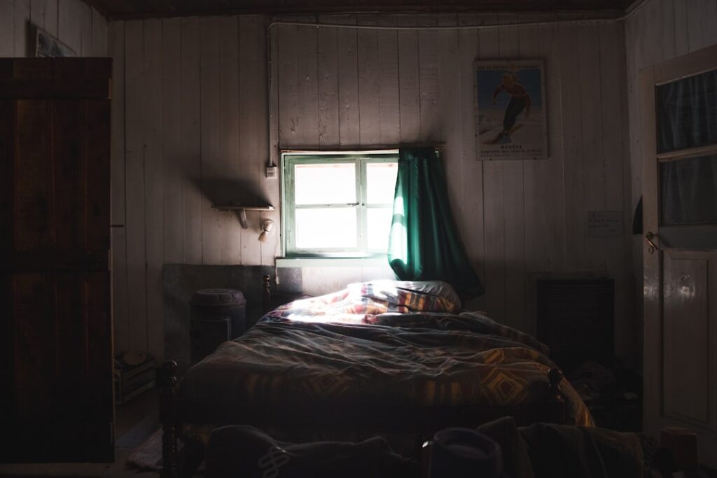 Dimly lit bedroom with a bed and window.