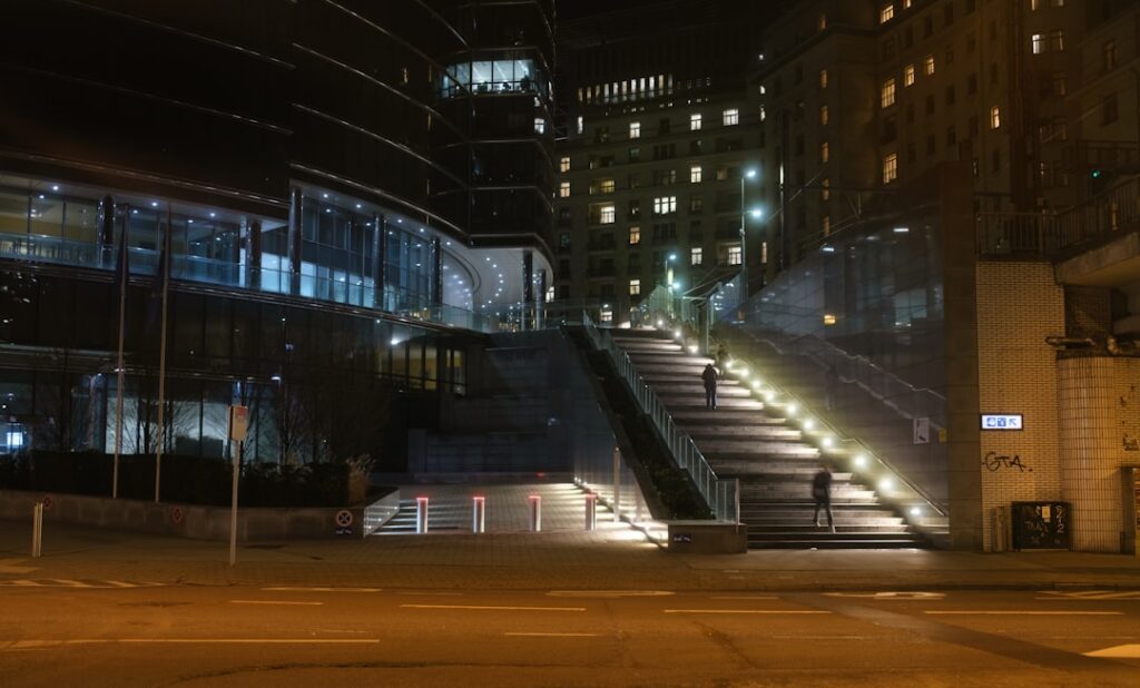Modern illuminated staircase leading up to buildings at night