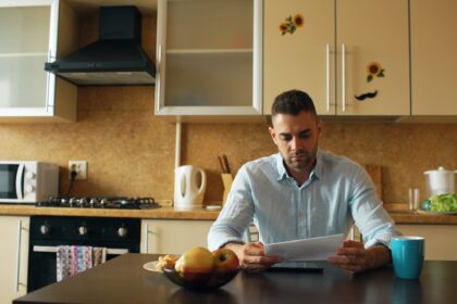 Man reading document at kitchen table with coffee