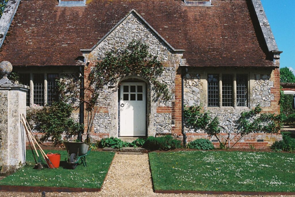 Stone cottage with a white door and garden tools