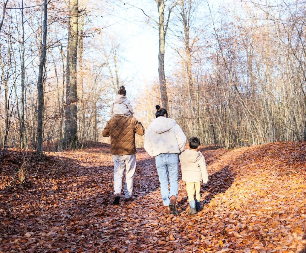 Family walking on a path in an autumn forest.