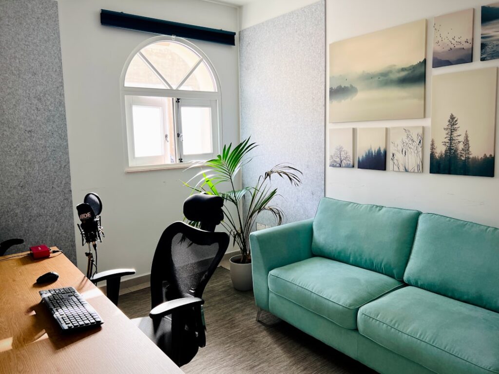 Modern office with desk, chair, and teal couch.