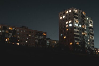 Apartment buildings glowing with lights at night.