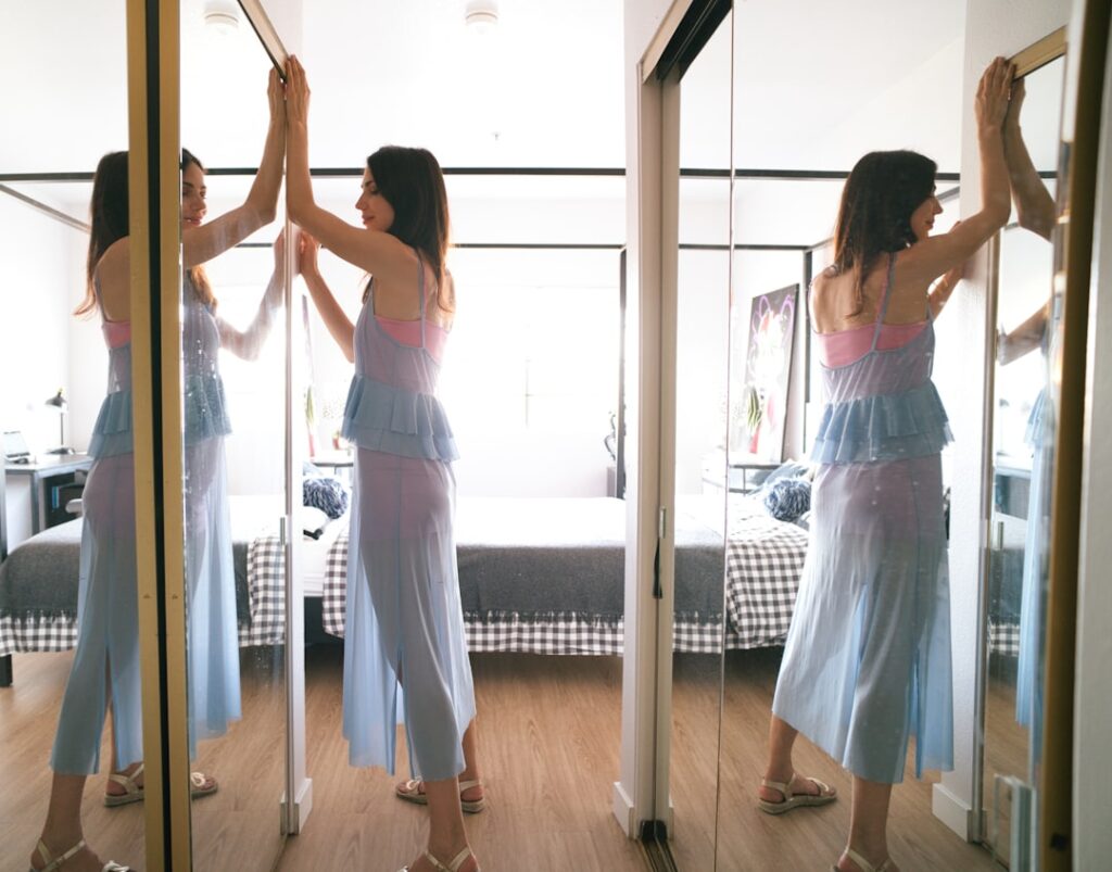 Woman stands in front of mirrors, seeing multiple reflections.