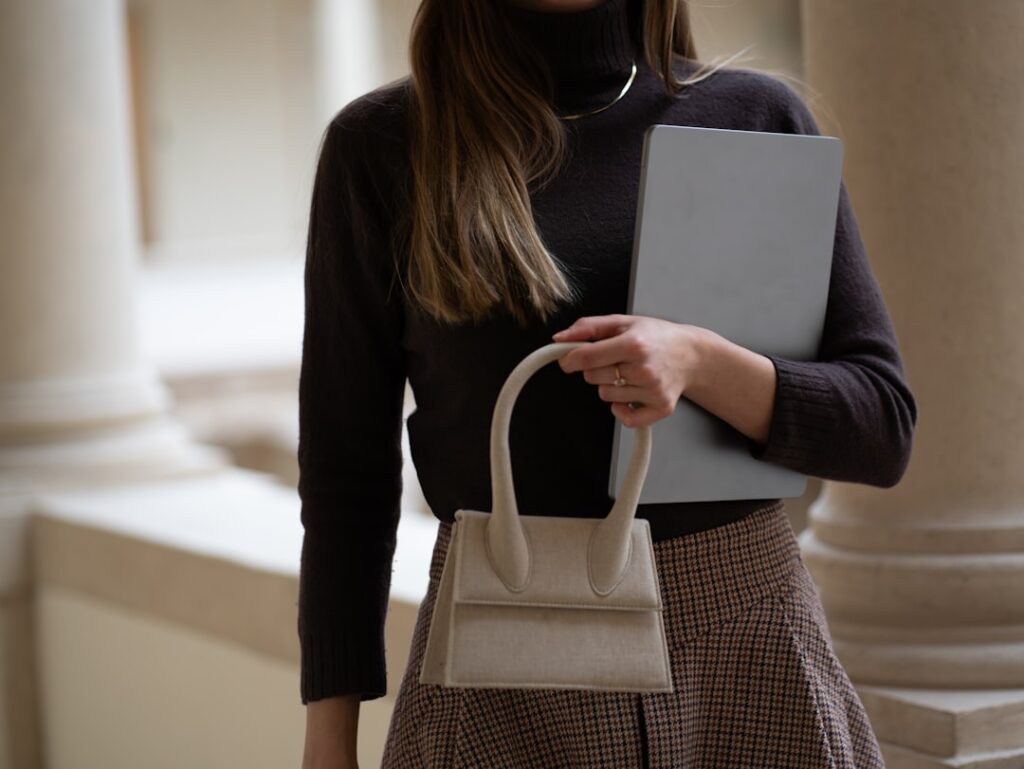 Woman holds a bag and a computer.