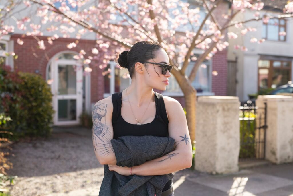 Woman with tattoos wearing sunglasses and black tank top.