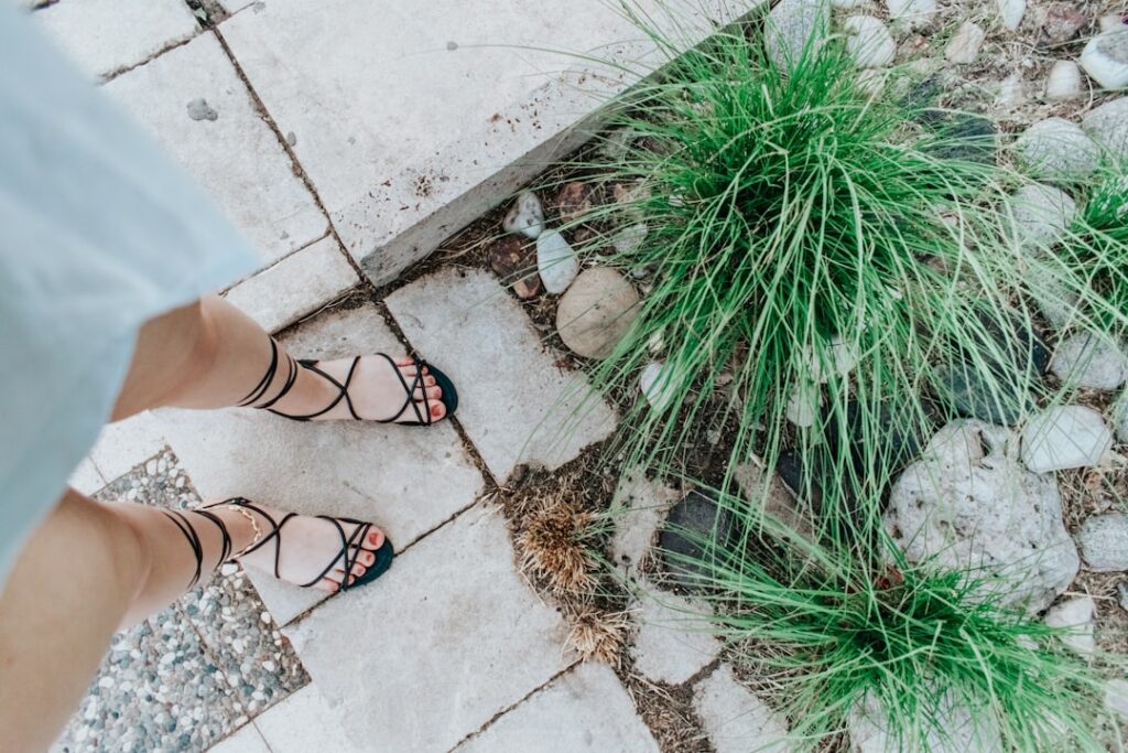 person wearing black leather sandals standing on gray concrete floor