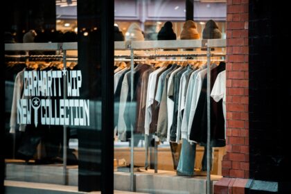 Clothes displayed on racks inside a store window.