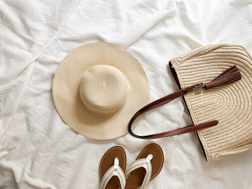 a pair of sandals and a hat on a bed