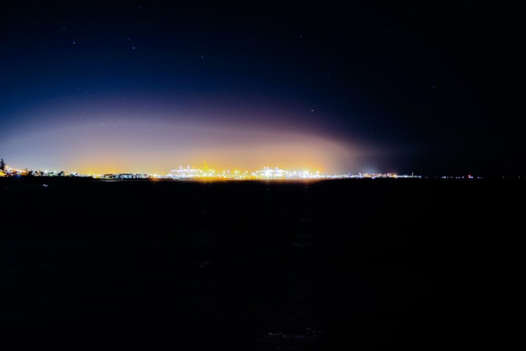 Distant city lights glow under a starry night sky.