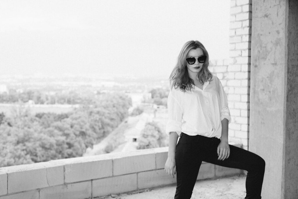 woman in white long sleeve shirt and black pants standing on concrete wall