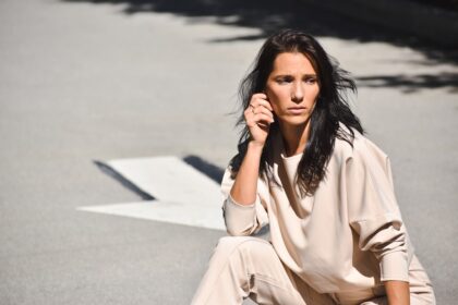 a woman sitting on the ground talking on a cell phone