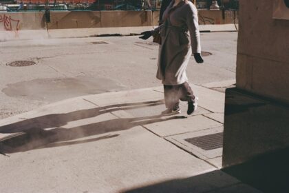 Person walking on a sidewalk casting long shadows.
