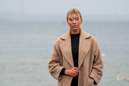 Woman in a beige coat by the water