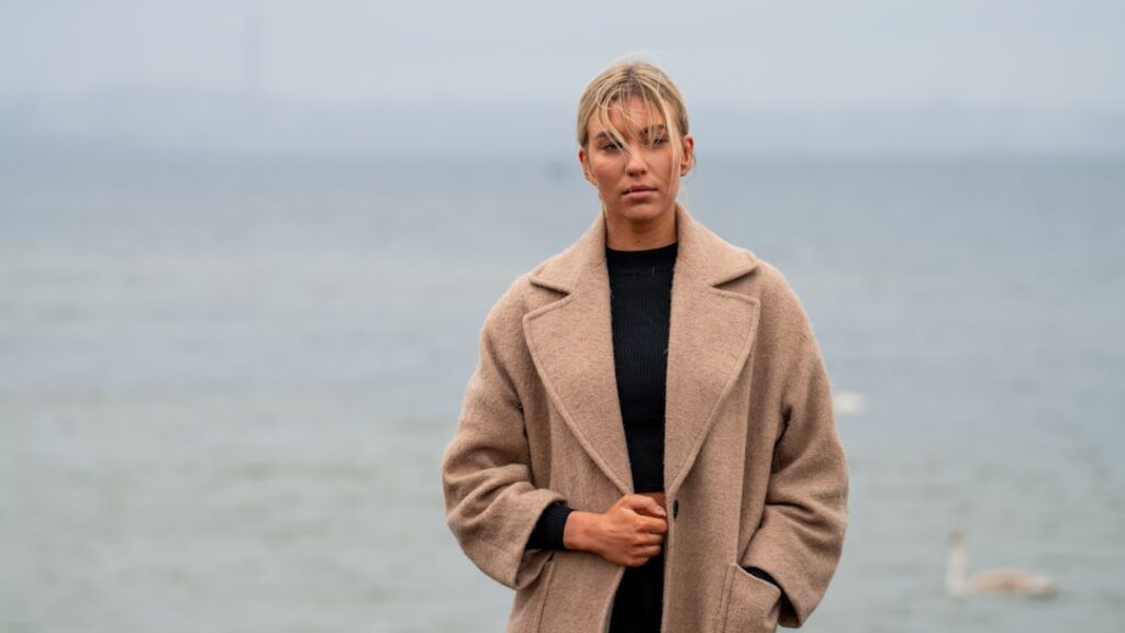 Woman in a beige coat by the water