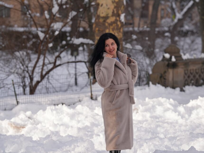A woman in a coat stands in the snow.