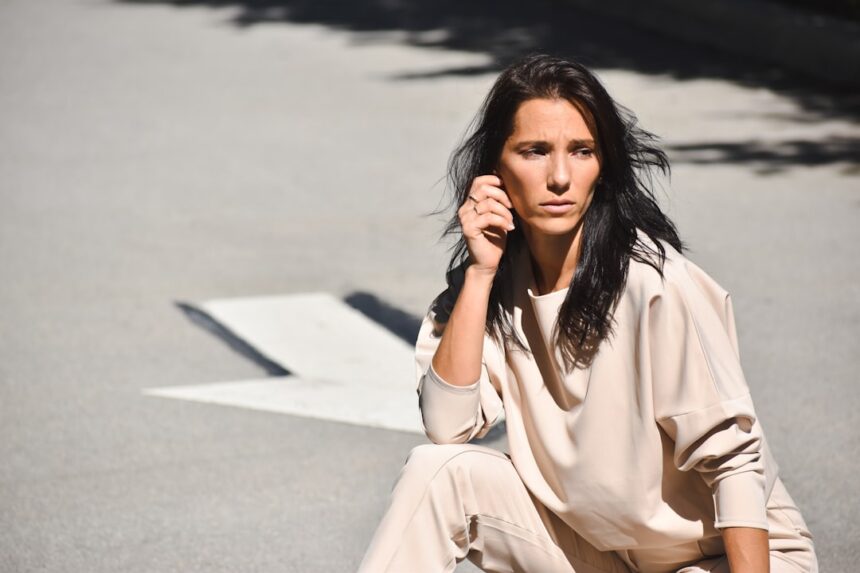 a woman sitting on the ground talking on a cell phone