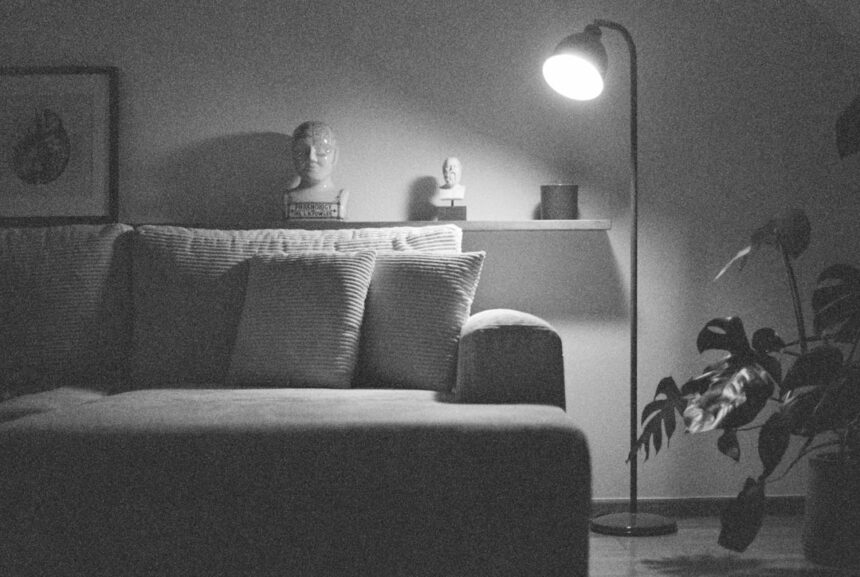 A dimly lit living room with a couch and lamp