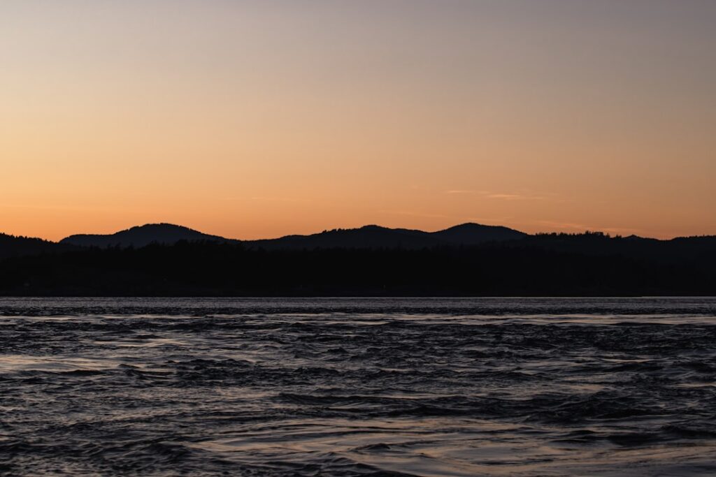 a sunset over a body of water with mountains in the background